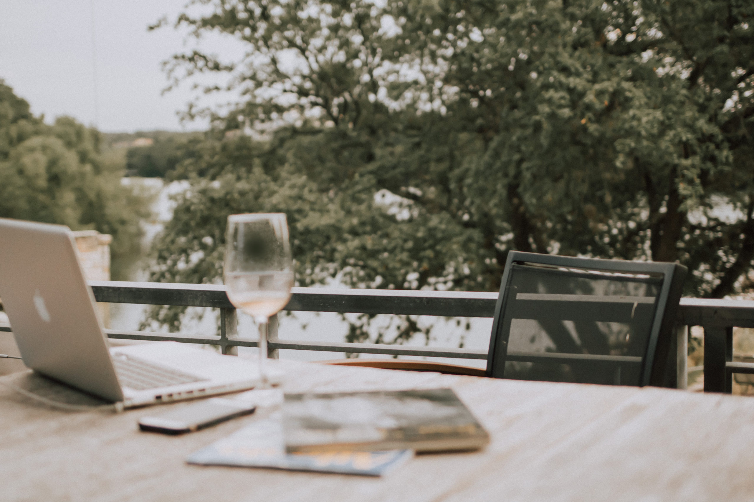 Wine glass and laptop on outdoor deck. Photo by Christin Hume on Unsplash.