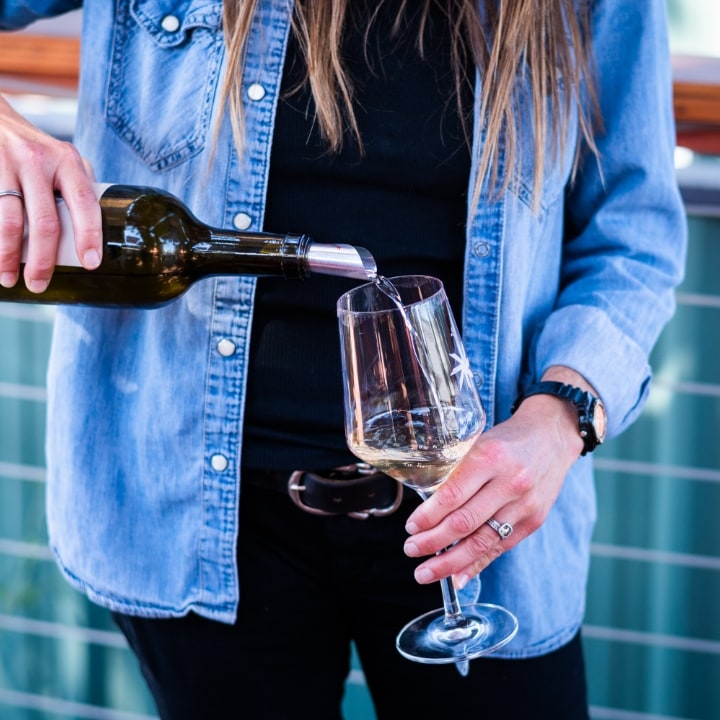 a person pouring a glass of white wine