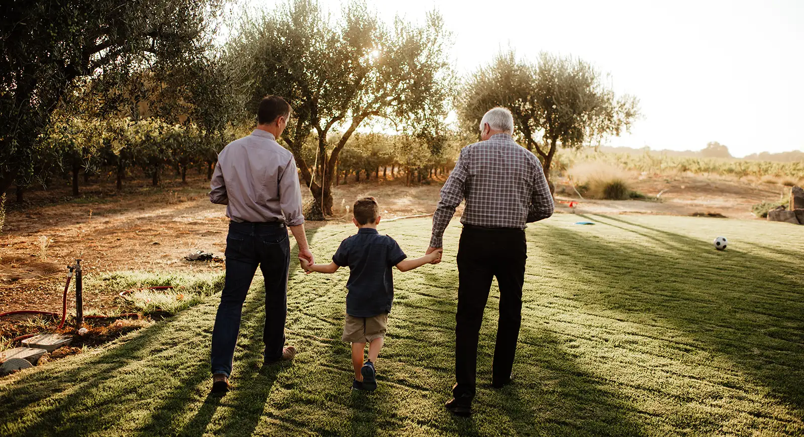 Three generations walking through a field.